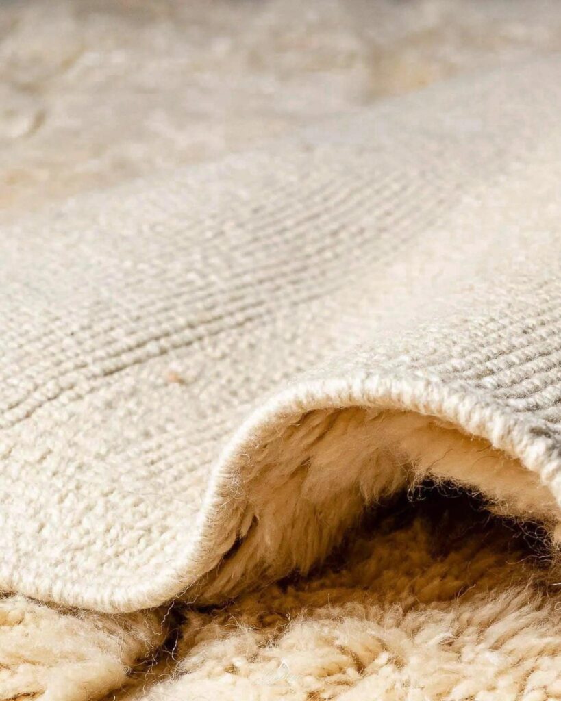 Close-up of a handwoven Beni Ourain rug showing thick natural wool pile and soft texture on the underside.