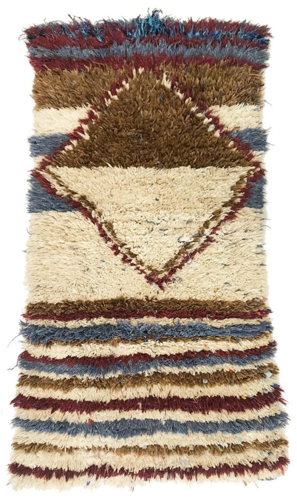 Handwoven Moroccan Berber rug with thick wool pile, featuring layered geometric diamond shapes and horizontal stripes in ivory, brown, blue, and red tones.