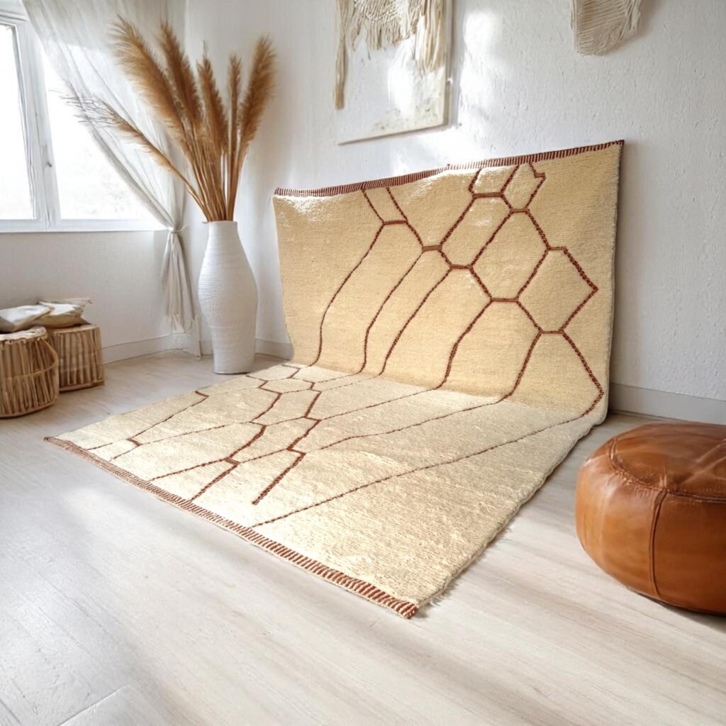 Authentic Beni Ourain rug in natural ivory wool with warm brown geometric lines, styled in a light-filled minimalist interior.