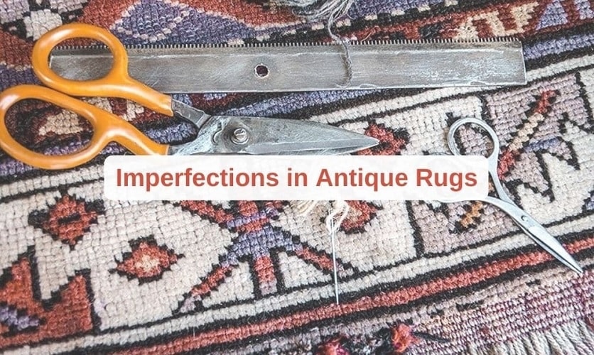 Close-up of an antique rug with visible handwoven imperfections, scissors and repair tools resting on the patterned surface.