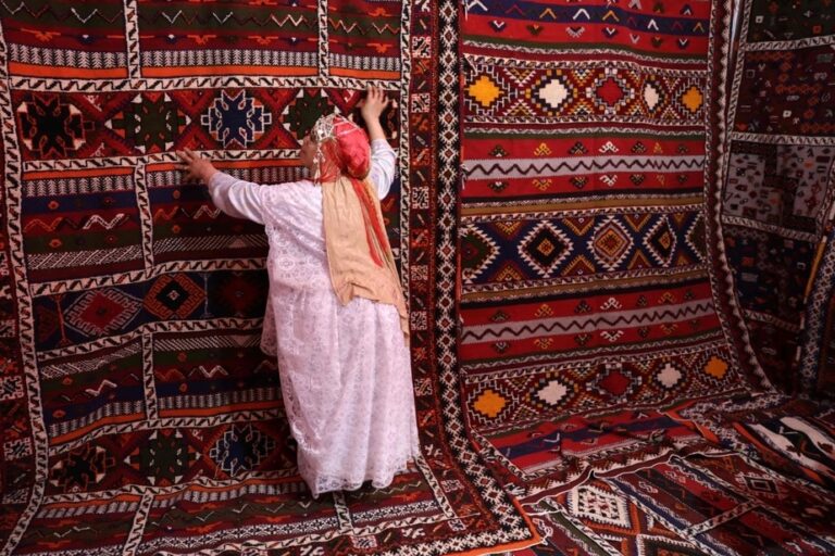 Berber woman inspecting a handwoven Moroccan Tazenakht rug with bold geometric patterns and natural dyes