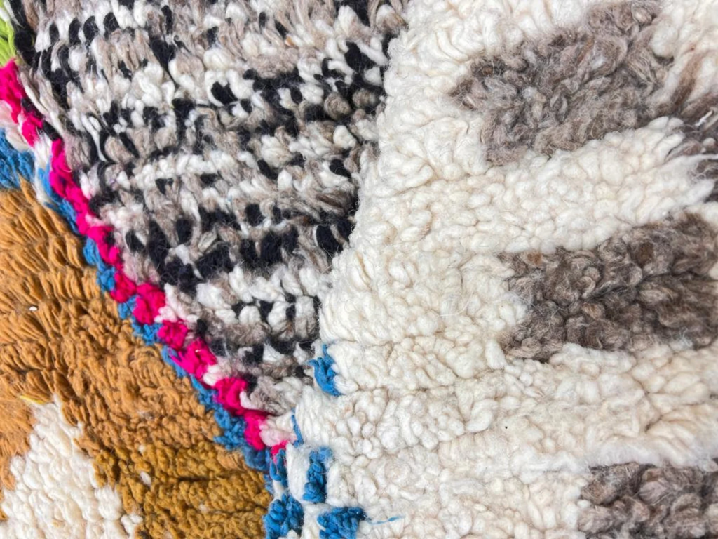 Close-up of a handwoven Moroccan Berber wool rug showing thick textured pile and colorful woven patterns.