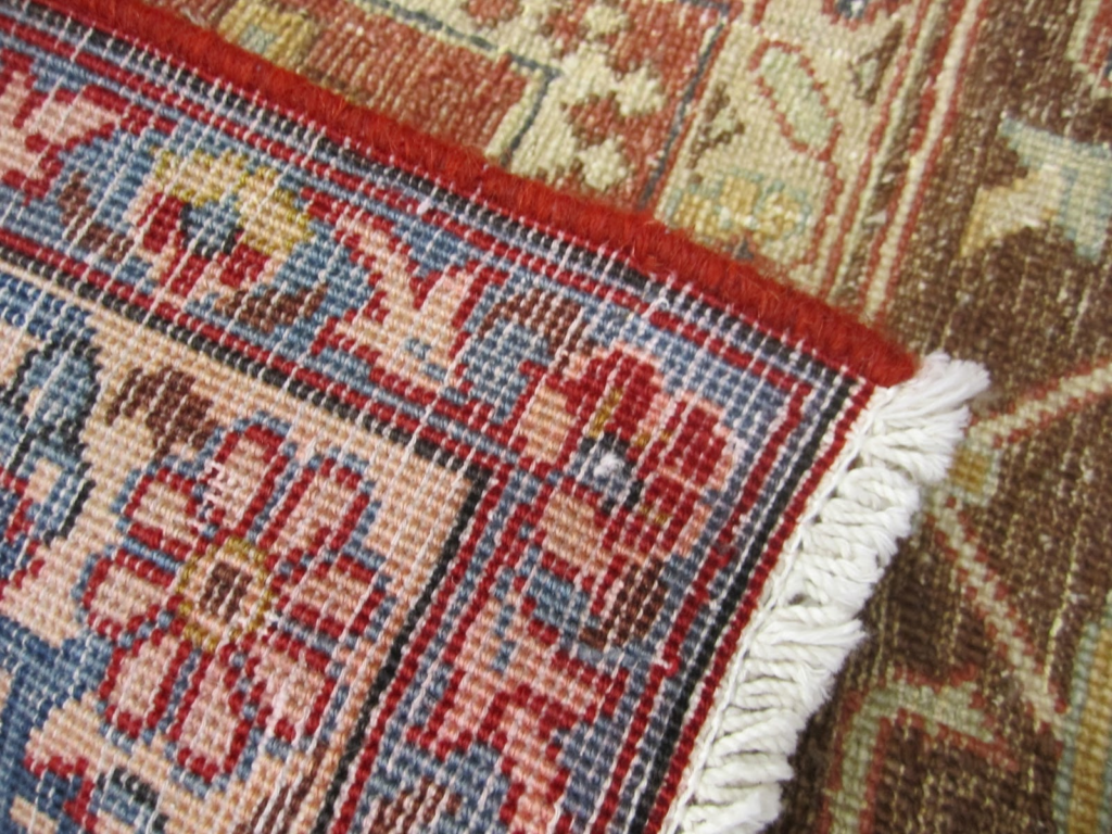 Close-up of the back of a tightly woven rug showing machine-made pattern and fringe detail, often used to identify rug authenticity.