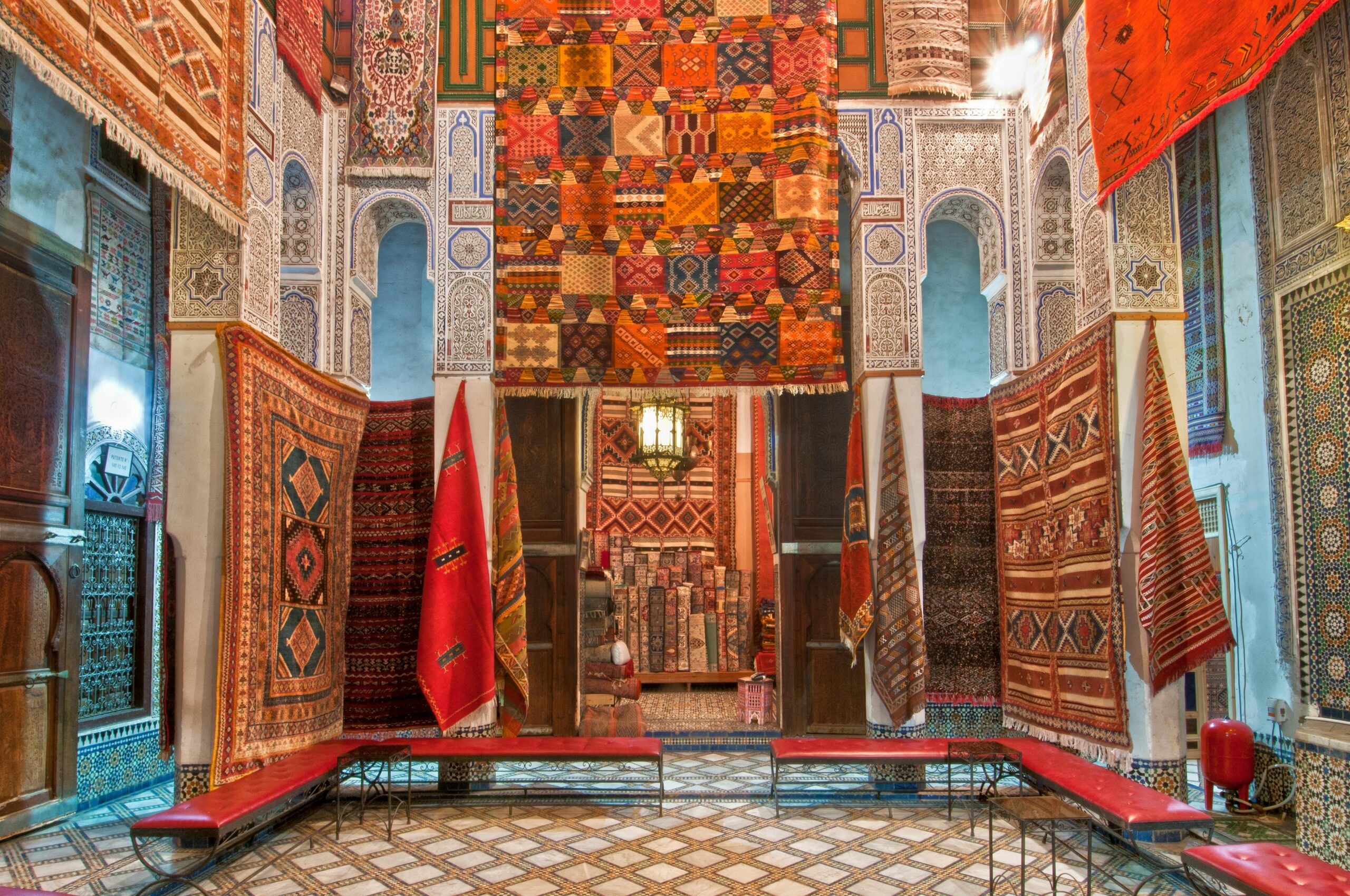 Moroccan Berber rug store featuring vibrant handwoven carpets, tribal patterns, and mosaic tile décor inside a historic medina building.