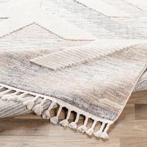 Close-up of a handwoven Moroccan rug showing subtle geometric patterns, low wool pile, and braided fringe, highlighting texture and natural fibers.