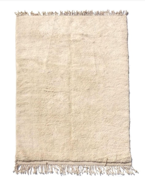 Authentic Beni Ourain rug in natural ivory wool with subtle texture and hand-knotted fringe, displayed flat.