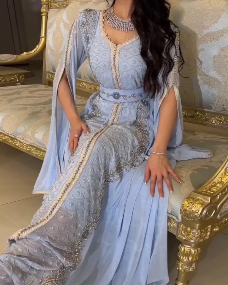 Woman wearing a traditional Moroccan kaftan during a formal celebration, featuring intricate embroidery, a fitted belt, and flowing ceremonial layers.