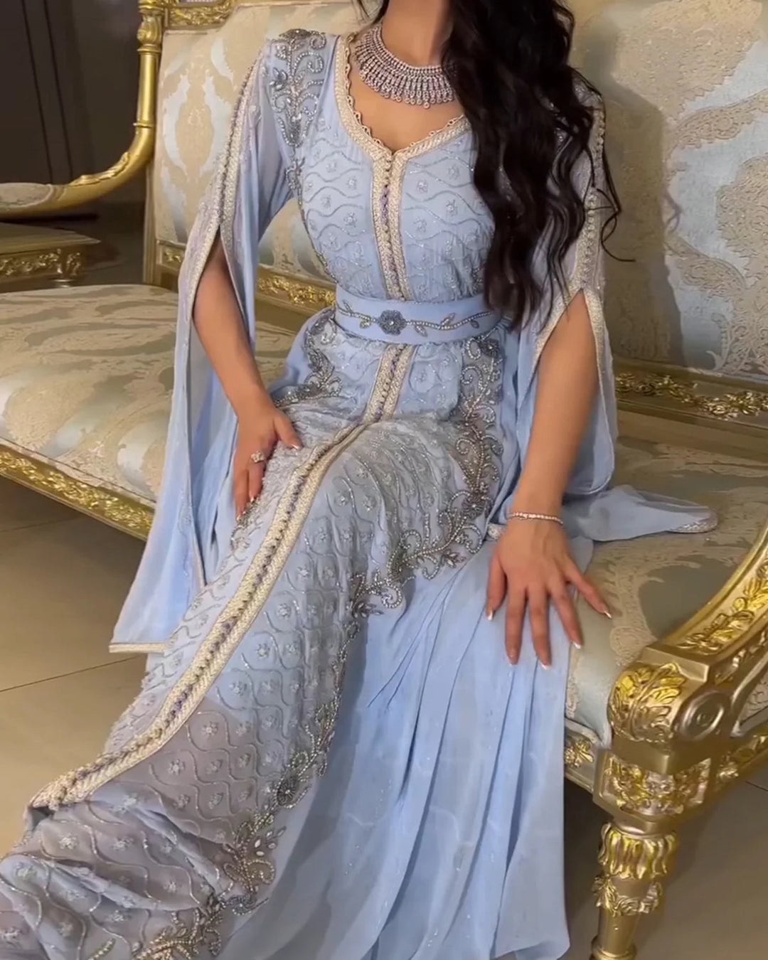Woman wearing a traditional Moroccan kaftan during a formal celebration, featuring intricate embroidery, a fitted belt, and flowing ceremonial layers.