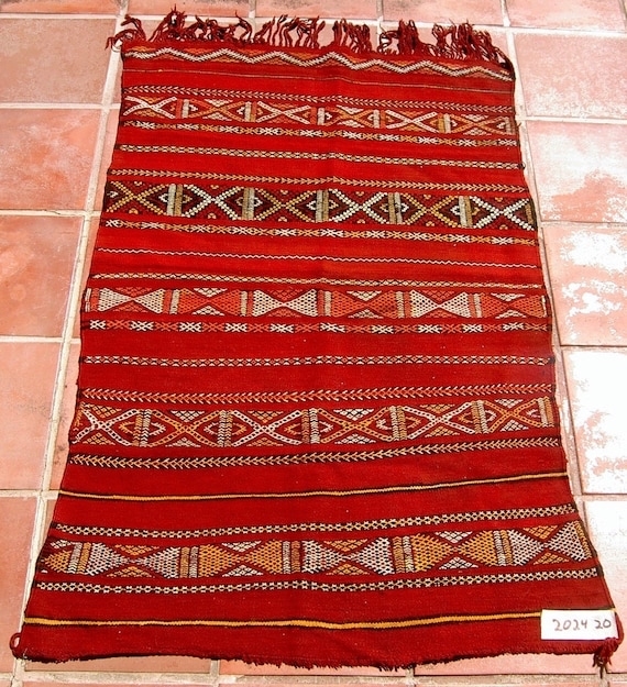 Authentic Moroccan kilim rug laid flat, showing traditional flatwoven structure, geometric patterns, and natural wool texture.