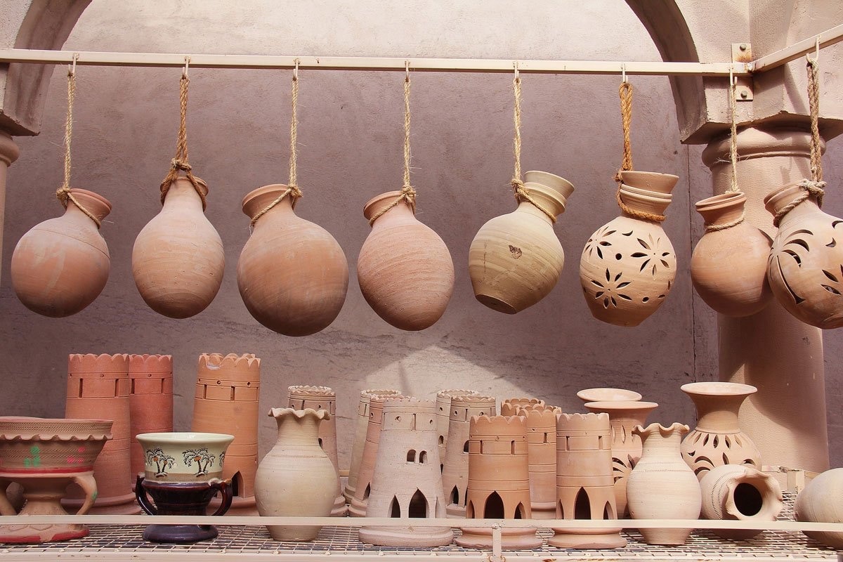 Traditional Moroccan Berber clay pottery drying on shelves, featuring handmade earthen jars and vessels with natural textures