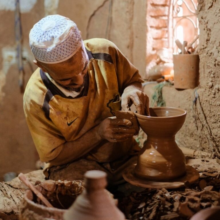 A Moroccan artisan shaping clay by hand on a traditional pottery wheel, showing the natural variations and imperfections of handmade ceramic craft.